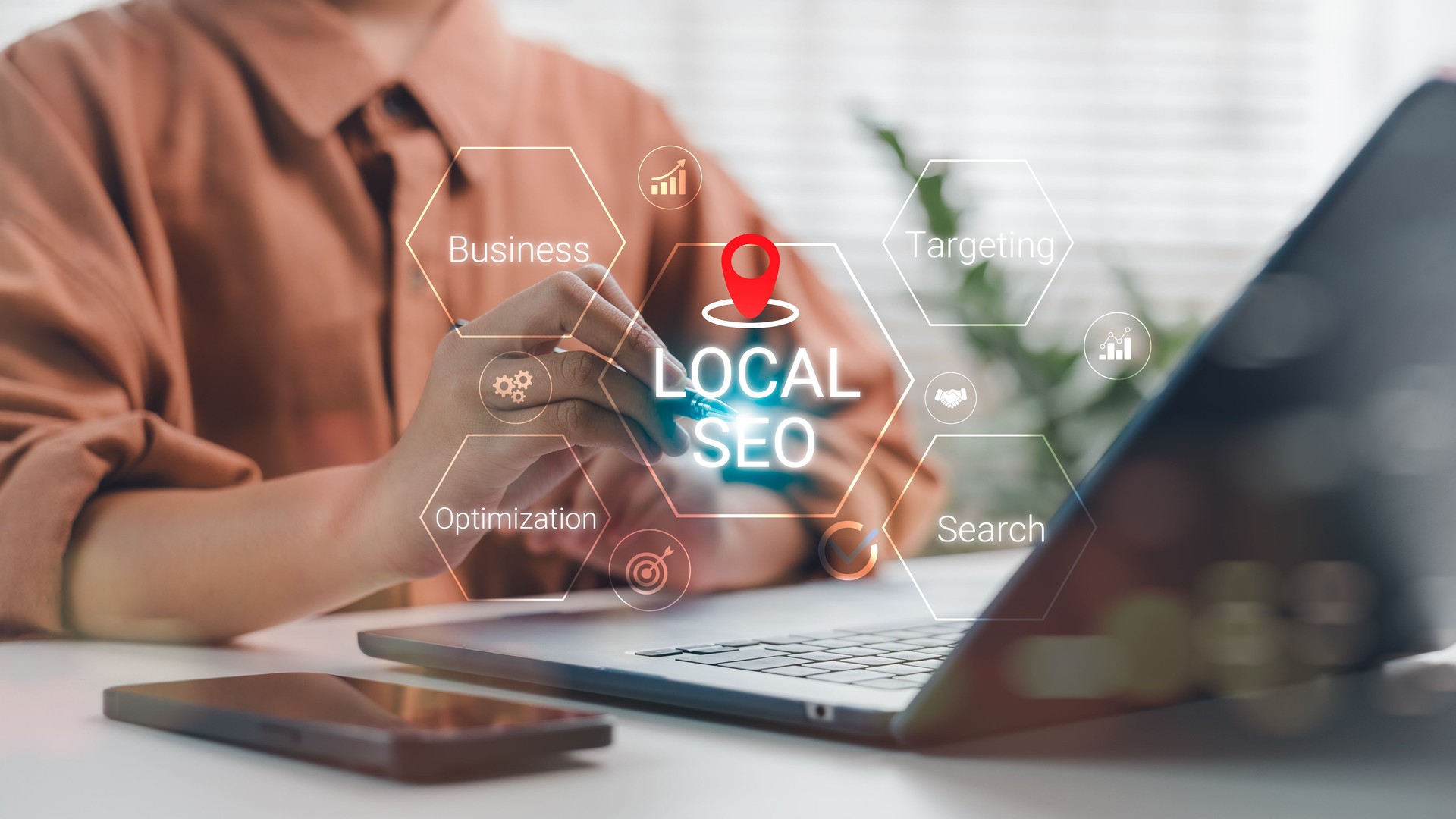 Business person working on laptop with Local SEO hologram and strategic keywords like optimization, targeting, and search, representing digital marketing and local business visibility.
